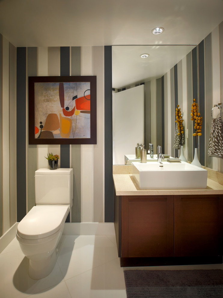 Powder room - mid-sized contemporary white tile ceramic tile powder room idea in Miami with flat-panel cabinets, dark wood cabinets, a one-piece toilet, beige walls and a vessel sink