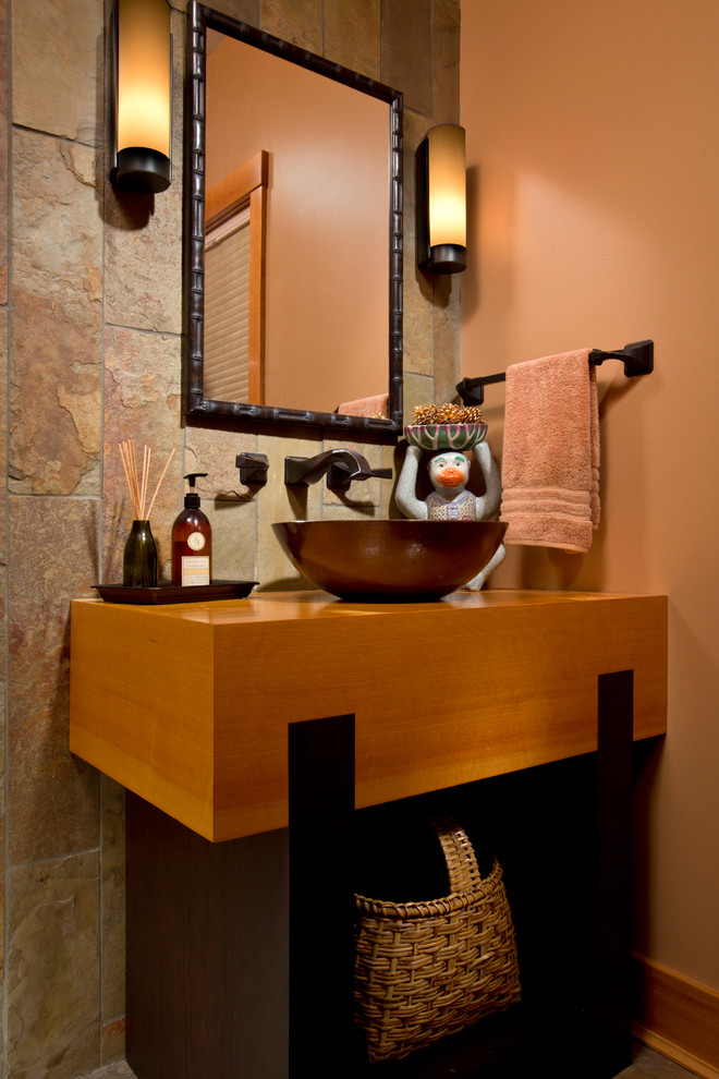 Inspiration for a medium sized traditional cloakroom in Boston with a vessel sink, orange walls, freestanding cabinets, light wood cabinets, stone tiles, wooden worktops and brown worktops.