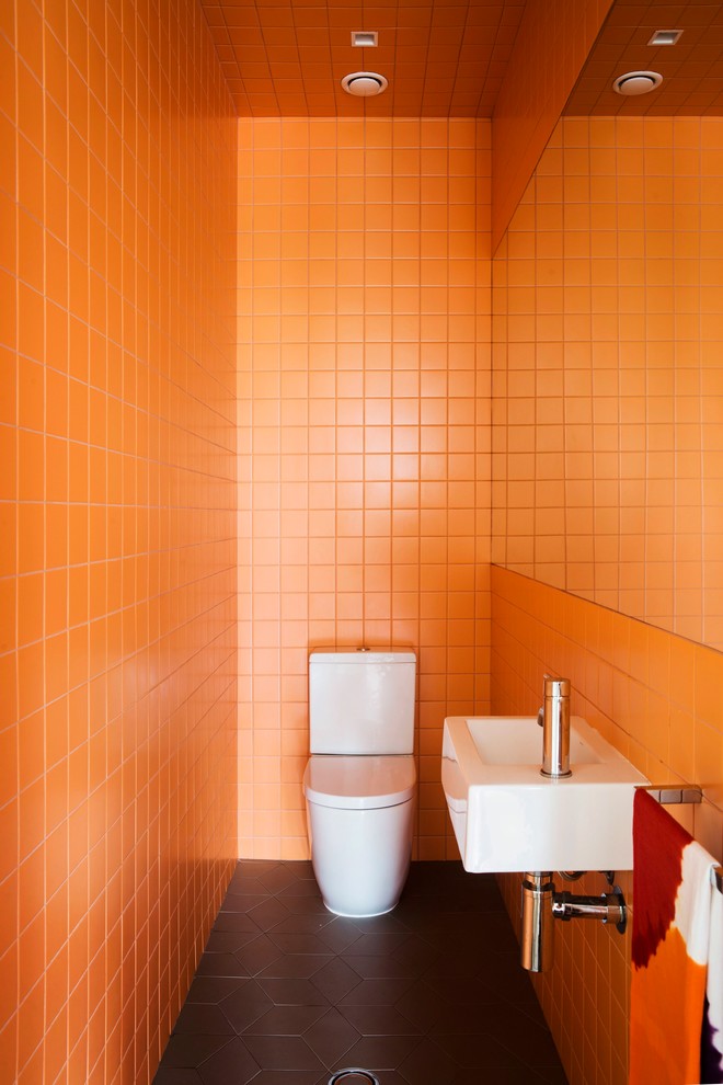 Idéer för ett litet modernt toalett, med ett väggmonterat handfat, orange kakel, keramikplattor, orange väggar, klinkergolv i porslin och en toalettstol med separat cisternkåpa