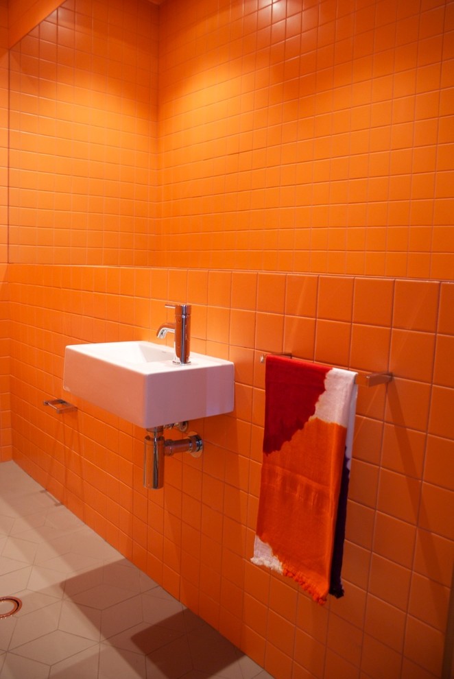 На фото: маленький туалет в современном стиле с подвесной раковиной, раздельным унитазом, оранжевой плиткой, керамической плиткой, оранжевыми стенами и полом из керамогранита для на участке и в саду