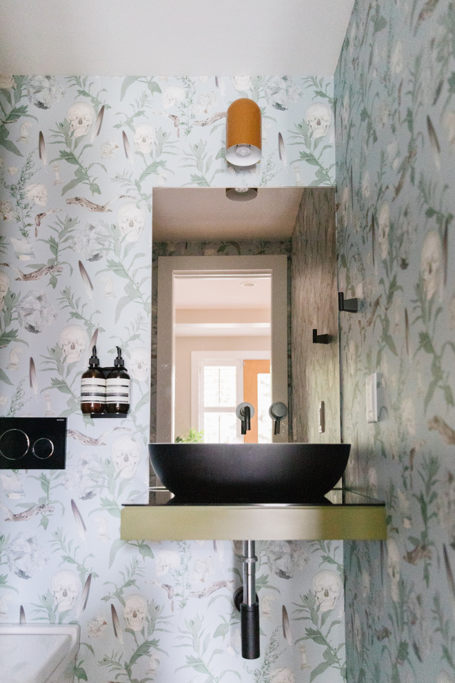 Inredning av ett eklektiskt stort svart svart toalett, med öppna hyllor, gröna skåp, en vägghängd toalettstol, glasskiva, flerfärgade väggar, klinkergolv i keramik, ett fristående handfat, bänkskiva i glas och flerfärgat golv