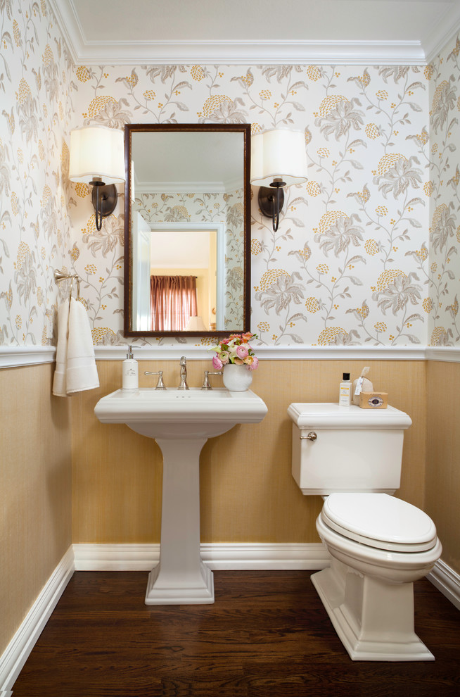 Bild på ett mellanstort vintage toalett, med en toalettstol med separat cisternkåpa, flerfärgade väggar, mörkt trägolv, ett piedestal handfat och brunt golv