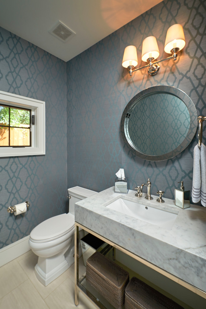 Klassisk inredning av ett litet toalett, med ett undermonterad handfat, öppna hyllor, marmorbänkskiva, en toalettstol med separat cisternkåpa, beige kakel, blå väggar och klinkergolv i porslin