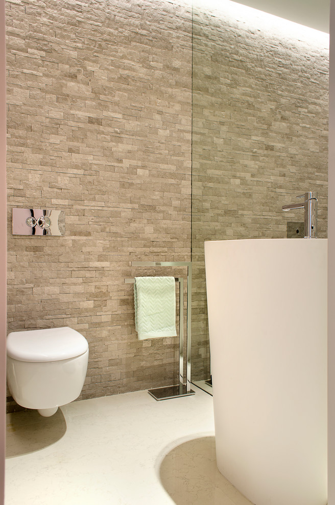 Example of a small minimalist gray tile and stone tile limestone floor powder room design in Other with a wall-mount toilet, gray walls and a pedestal sink