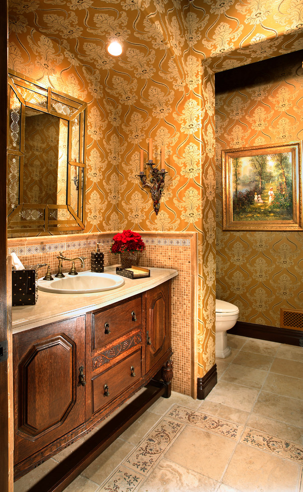 Example of a tuscan multicolored tile and mosaic tile travertine floor powder room design in Los Angeles with a drop-in sink, furniture-like cabinets, dark wood cabinets, multicolored walls, travertine countertops and a one-piece toilet