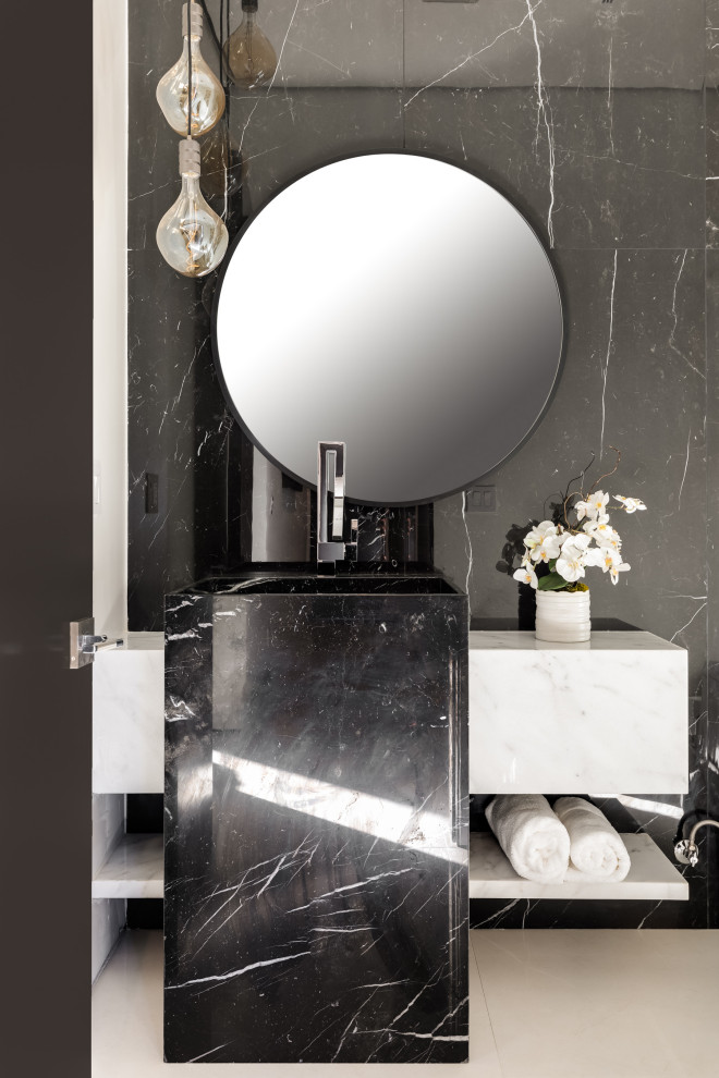 Bild på ett mellanstort funkis svart svart toalett, med en toalettstol med hel cisternkåpa, svart och vit kakel, stenkakel, vita väggar, klinkergolv i porslin, ett piedestal handfat, marmorbänkskiva och vitt golv