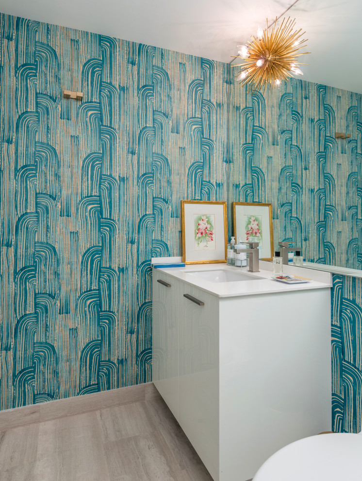 Moderne Gästetoilette mit flächenbündigen Schrankfronten, weißen Schränken, hellem Holzboden, Unterbauwaschbecken, blauer Wandfarbe und grauem Boden in Miami
