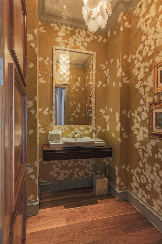Inredning av ett modernt toalett, med ett fristående handfat, träbänkskiva, flerfärgade väggar och mellanmörkt trägolv
