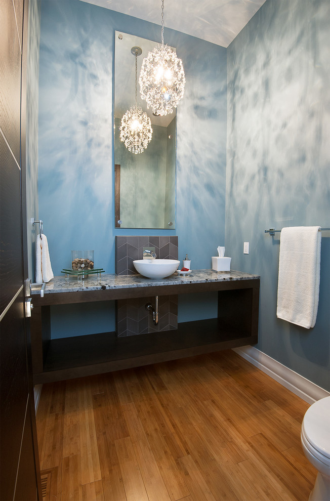 Modern inredning av ett mellanstort toalett, med ett fristående handfat, skåp i mörkt trä, marmorbänkskiva, porslinskakel, blå väggar, bambugolv och öppna hyllor