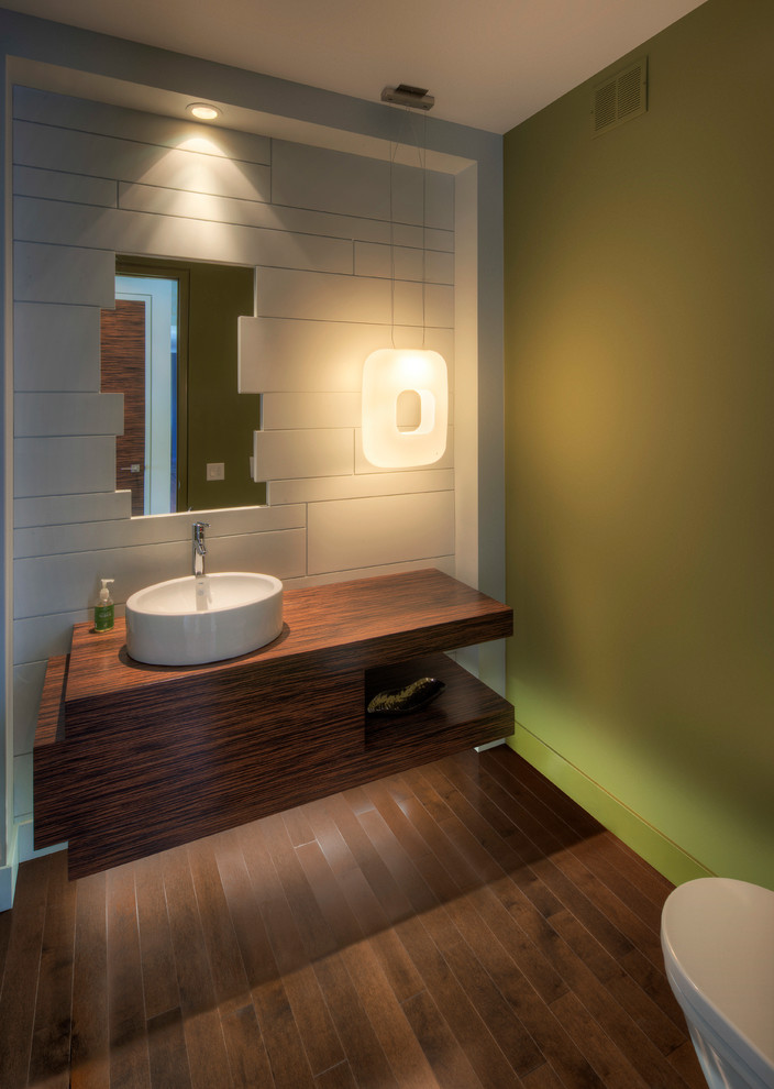 Große Moderne Gästetoilette mit Aufsatzwaschbecken, Waschtisch aus Holz, flächenbündigen Schrankfronten, hellbraunen Holzschränken, Toilette mit Aufsatzspülkasten, grüner Wandfarbe und braunem Holzboden in Sonstige