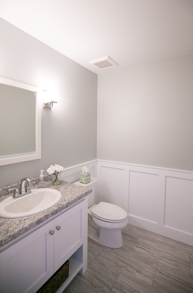 Exemple d'un WC et toilettes craftsman avec un placard à porte plane, des portes de placard blanches, un plan de toilette en stratifié, un carrelage gris, un mur gris, un sol en carrelage de porcelaine, un lavabo posé et un sol beige.