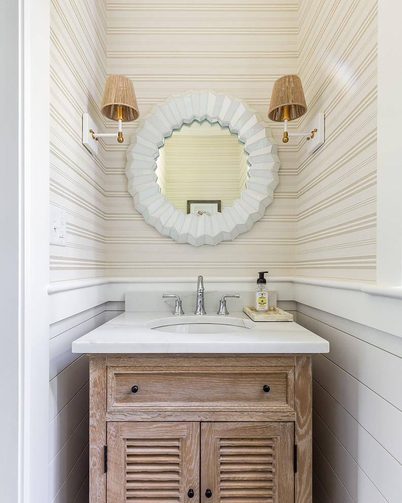 Small beach style cloakroom in Boston with louvered cabinets, light wood cabinets, beige walls, a submerged sink, white worktops, a freestanding vanity unit and wallpapered walls.