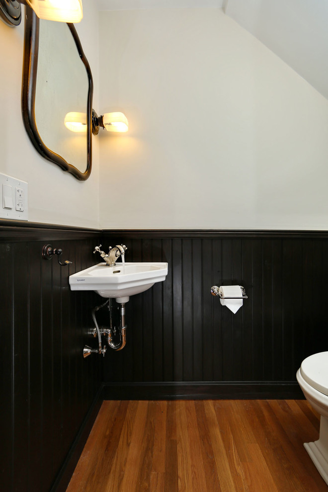 Kleine Stilmix Gästetoilette mit Wandwaschbecken, schwarzer Wandfarbe und braunem Holzboden in Boston