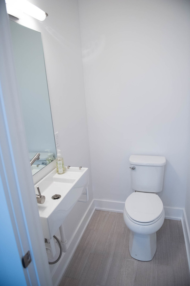 Idéer för att renovera ett litet funkis toalett, med öppna hyllor, en toalettstol med separat cisternkåpa, vita väggar, laminatgolv, ett väggmonterat handfat, bänkskiva i akrylsten och grått golv