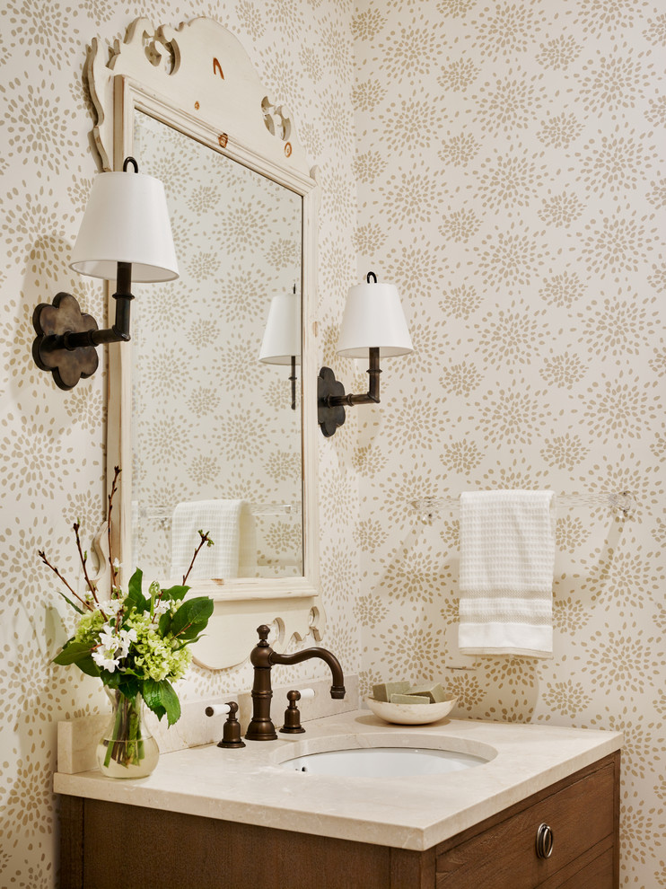 Inredning av ett klassiskt litet beige beige toalett, med möbel-liknande, skåp i mellenmörkt trä, en toalettstol med separat cisternkåpa, flerfärgade väggar, ett undermonterad handfat och bänkskiva i kalksten