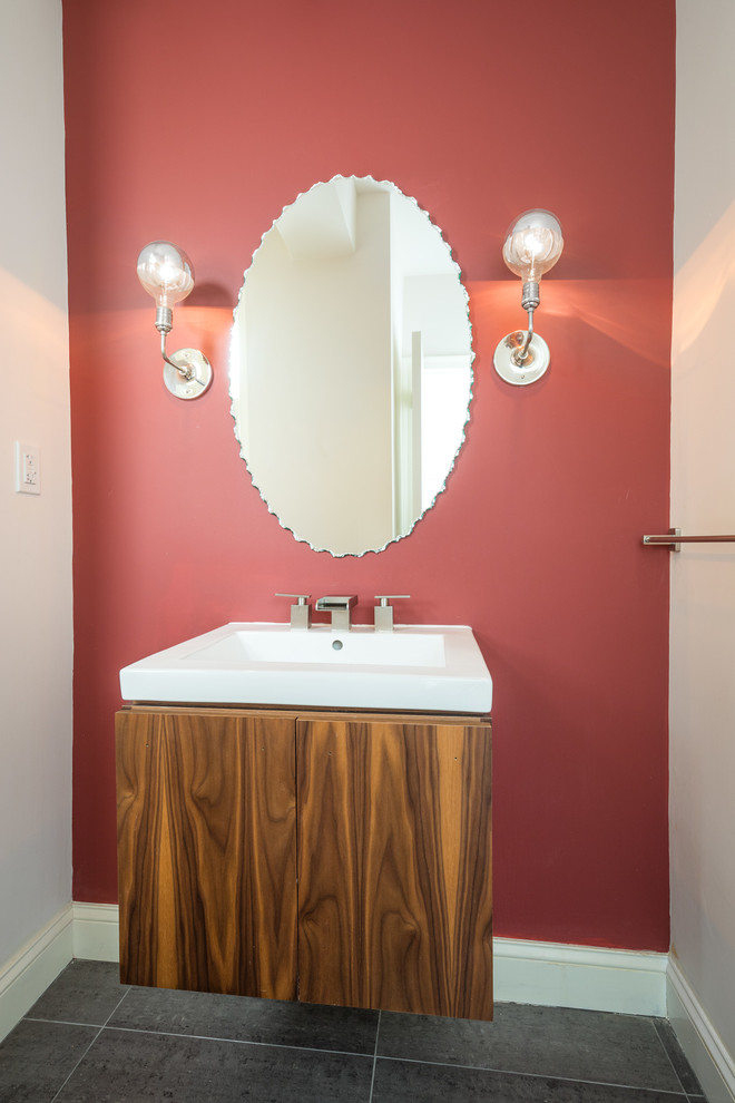 Idée de décoration pour un petit WC et toilettes tradition en bois brun avec un placard à porte plane, un mur rouge, un sol en carrelage de porcelaine, un lavabo intégré, un plan de toilette en surface solide et un sol gris.