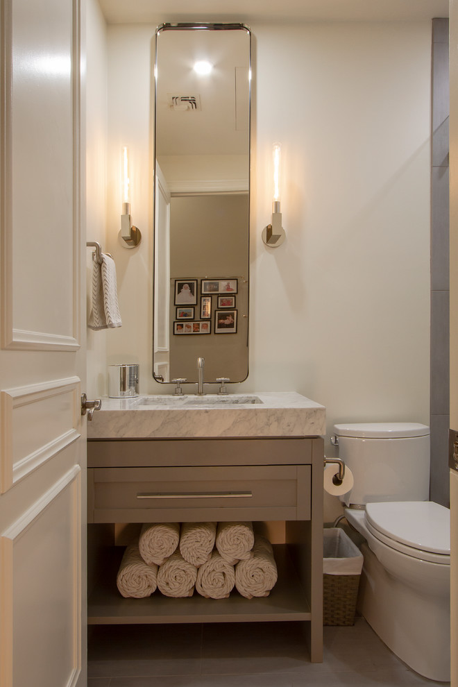 Cette image montre un WC et toilettes traditionnel avec un placard en trompe-l'oeil, des portes de placard grises, WC séparés, du carrelage en marbre, un mur gris, un sol en carrelage de porcelaine, une grande vasque, un plan de toilette en marbre et un sol gris.