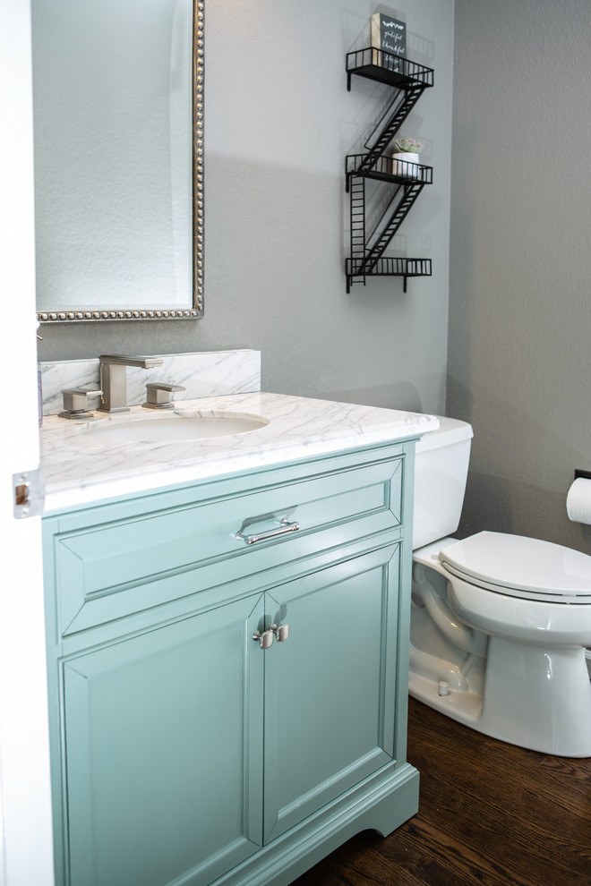 Mid-sized transitional yellow tile medium tone wood floor and brown floor powder room photo in Denver with recessed-panel cabinets, blue cabinets, a one-piece toilet, gray walls, an undermount sink, marble countertops and white countertops