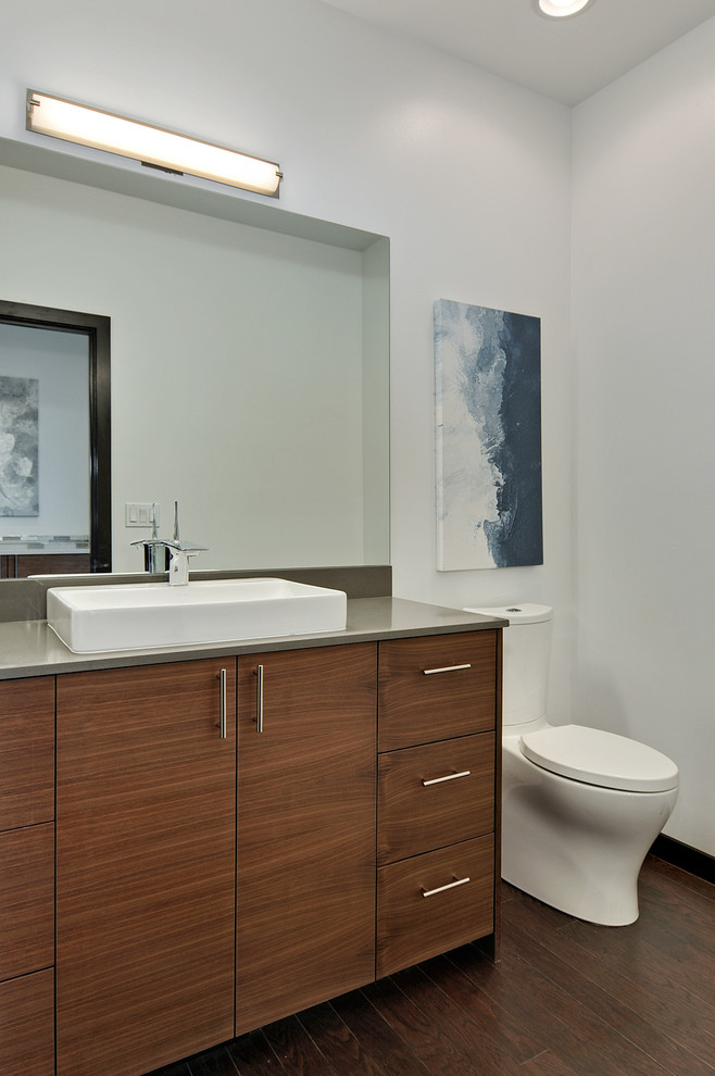 Exemple d'un WC et toilettes moderne en bois foncé de taille moyenne avec un placard à porte plane, WC à poser, un mur blanc, parquet foncé, une vasque, un plan de toilette en quartz modifié, un sol marron et un plan de toilette gris.