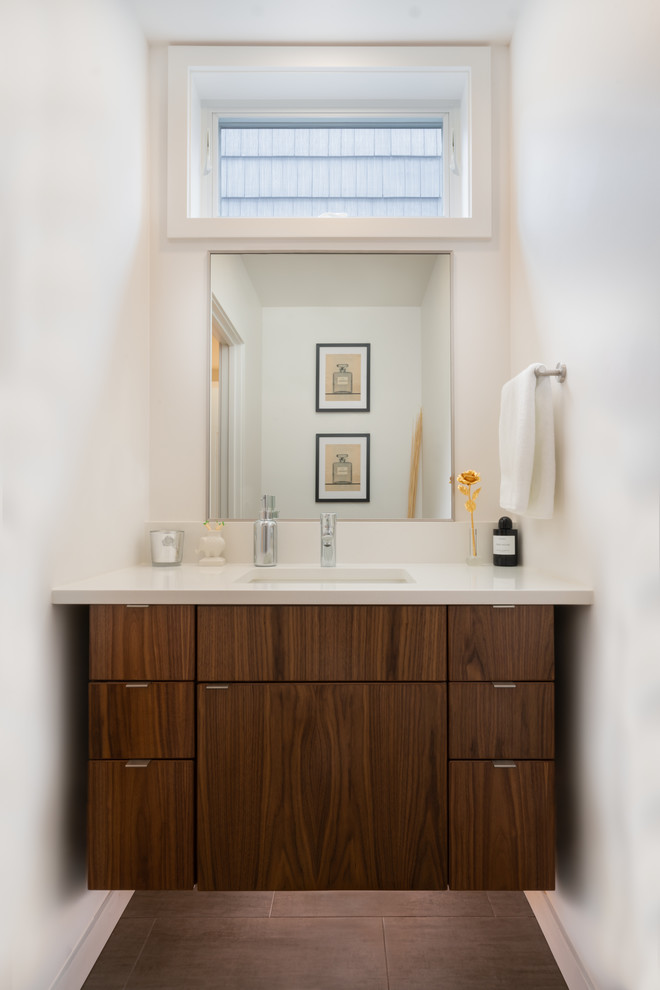 Design ideas for a medium sized contemporary cloakroom in Seattle with flat-panel cabinets, brown cabinets, a two-piece toilet, white tiles, white walls, porcelain flooring, a submerged sink, engineered stone worktops, grey floors and white worktops.