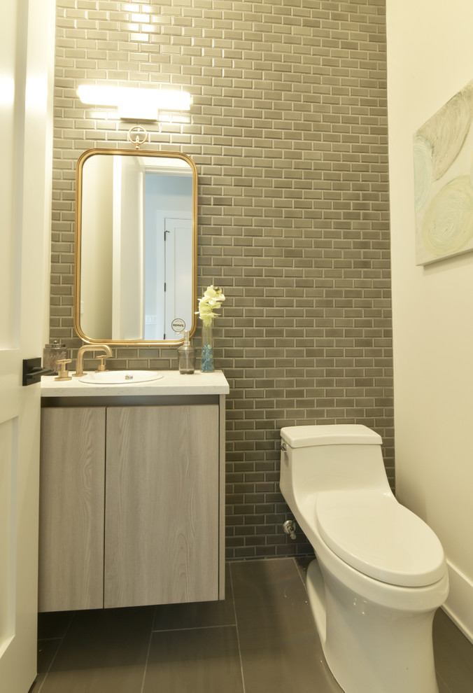 Inspiration for a small modern cloakroom in Chicago with grey cabinets, a one-piece toilet, grey tiles, ceramic tiles, white walls, ceramic flooring, a built-in sink, engineered stone worktops, grey floors and white worktops.