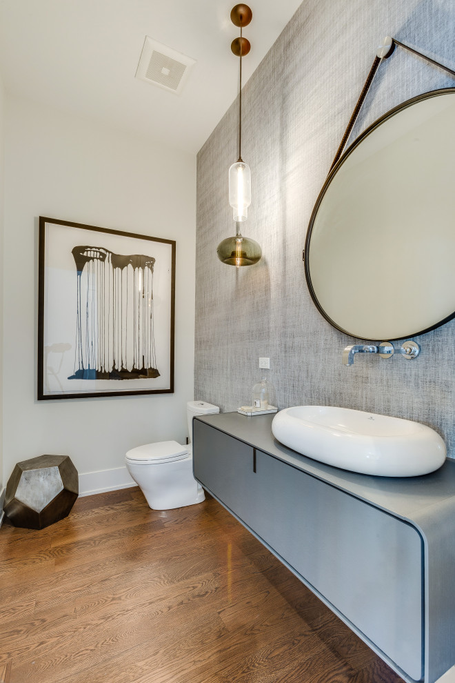 Contemporary cloakroom in Chicago with flat-panel cabinets, grey cabinets, a two-piece toilet, white walls, medium hardwood flooring, a vessel sink, brown floors, grey worktops, a floating vanity unit and wallpapered walls.