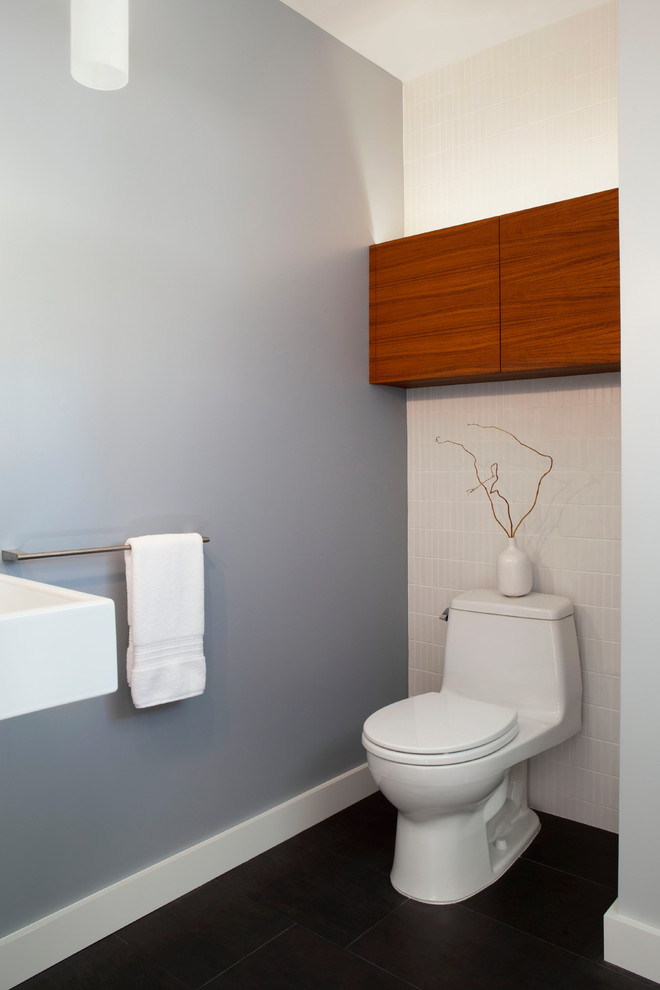 Idée de décoration pour un petit WC et toilettes tradition en bois brun avec un placard à porte plane, WC à poser, un carrelage blanc, des carreaux de céramique, un mur gris, un sol en carrelage de porcelaine, un lavabo suspendu et un sol gris.