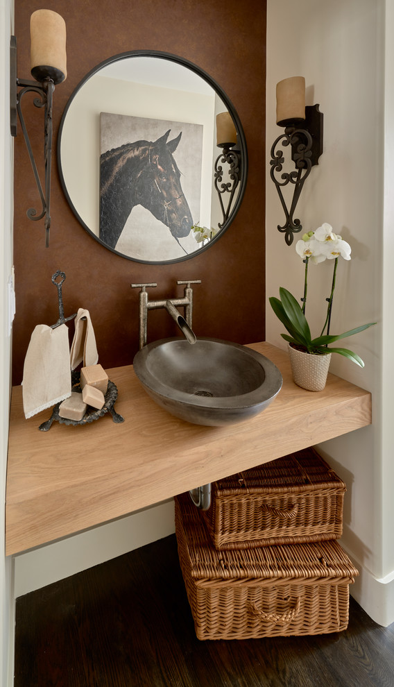 Foto på ett lantligt brun toalett, med öppna hyllor, vita väggar, mörkt trägolv, ett fristående handfat, träbänkskiva och brunt golv