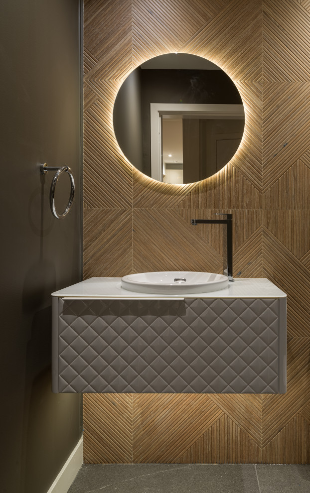 This is an example of a medium sized contemporary cloakroom in Vancouver with freestanding cabinets, white cabinets, a one-piece toilet, brown tiles, porcelain tiles, grey walls, porcelain flooring, a built-in sink, glass worktops, grey floors, white worktops and a floating vanity unit.