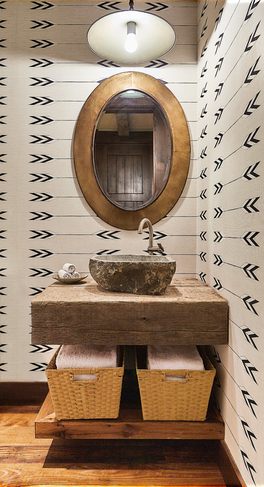 Cette image montre un WC et toilettes chalet avec un mur multicolore, un sol en bois brun et une vasque.