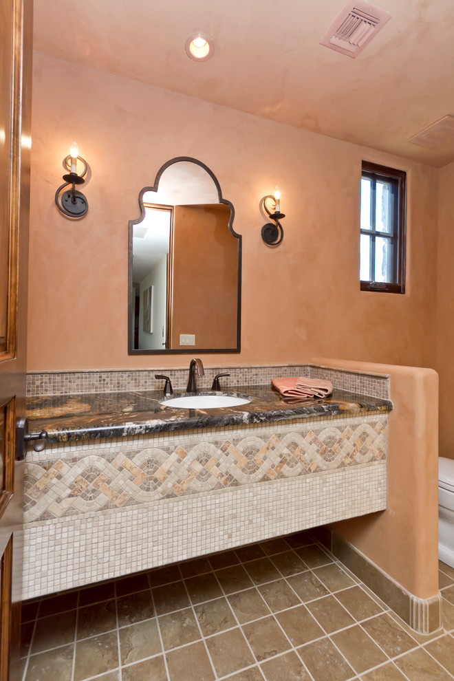 Foto di un bagno di servizio mediterraneo di medie dimensioni con lavabo sottopiano, top in granito, WC monopezzo, piastrelle beige, pavimento in travertino, pareti beige e piastrelle a mosaico