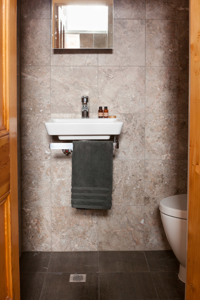 Immagine di un piccolo bagno di servizio vittoriano con lavabo sospeso, WC sospeso, piastrelle nere, piastrelle in pietra, pareti beige e pavimento in marmo