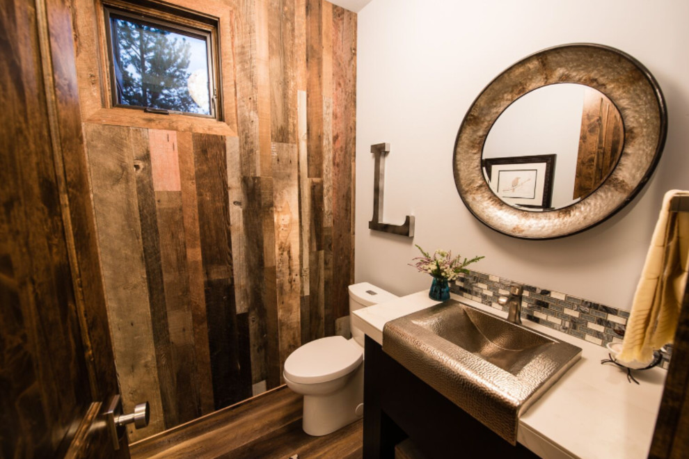 Cette image montre un WC et toilettes chalet en bois foncé de taille moyenne avec WC séparés, un mur blanc, parquet foncé, un lavabo posé et un plan de toilette en surface solide.
