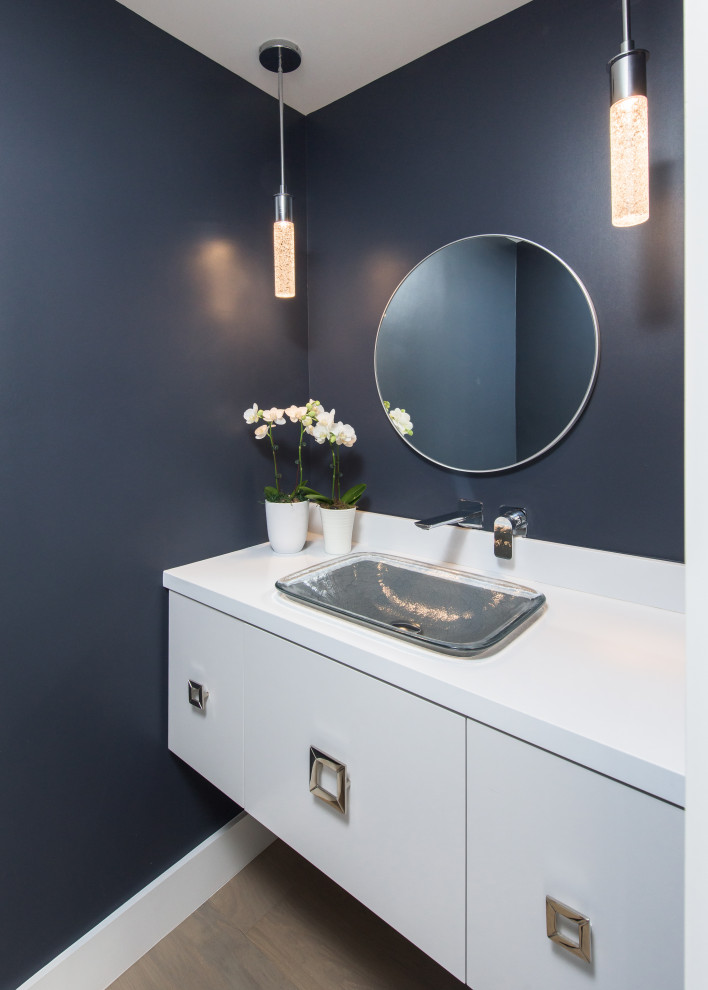 Photo of a small nautical cloakroom in Los Angeles with flat-panel cabinets, grey cabinets, a one-piece toilet, blue walls, medium hardwood flooring, a vessel sink, engineered stone worktops, brown floors, white worktops and a floating vanity unit.