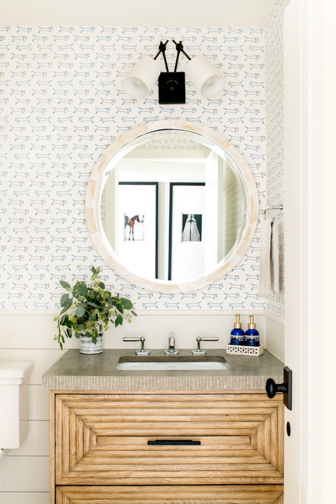 Lantlig inredning av ett grå grått toalett, med möbel-liknande, skåp i ljust trä, flerfärgade väggar och ett undermonterad handfat