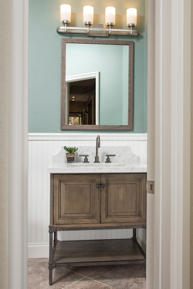This is an example of a medium sized traditional cloakroom in San Diego with raised-panel cabinets, beige tiles, green walls, a submerged sink, marble worktops, distressed cabinets and white worktops.