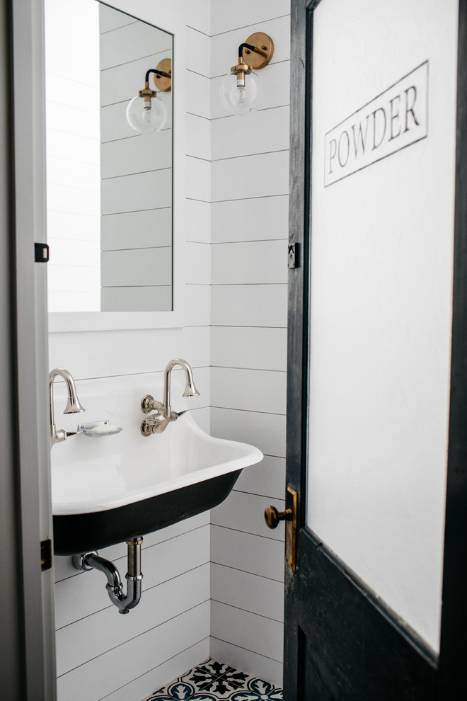 Foto på ett lantligt toalett, med vita väggar, cementgolv och ett avlångt handfat