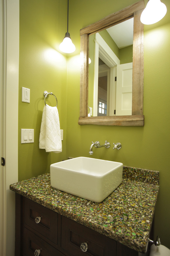 Idéer för att renovera ett litet vintage grön grönt toalett, med luckor med infälld panel, skåp i mörkt trä, en toalettstol med separat cisternkåpa, gröna väggar, mörkt trägolv, ett fristående handfat, bänkskiva i återvunnet glas och brunt golv