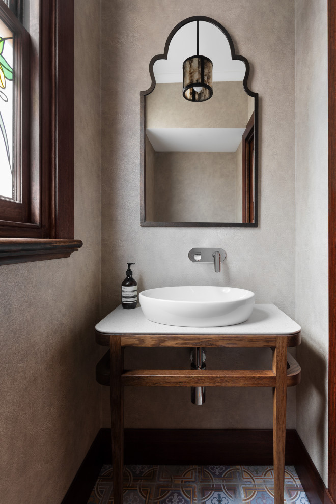 Cette photo montre un WC et toilettes méditerranéen en bois brun avec un placard sans porte, un mur beige, une vasque, un sol multicolore, un plan de toilette blanc et meuble-lavabo encastré.