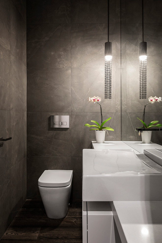 メルボルンにあるコンテンポラリースタイルのおしゃれなトイレ・洗面所 (白いキャビネット、人工大理石カウンター、一体型トイレ	、グレーのタイル、石タイル、グレーの壁) の写真