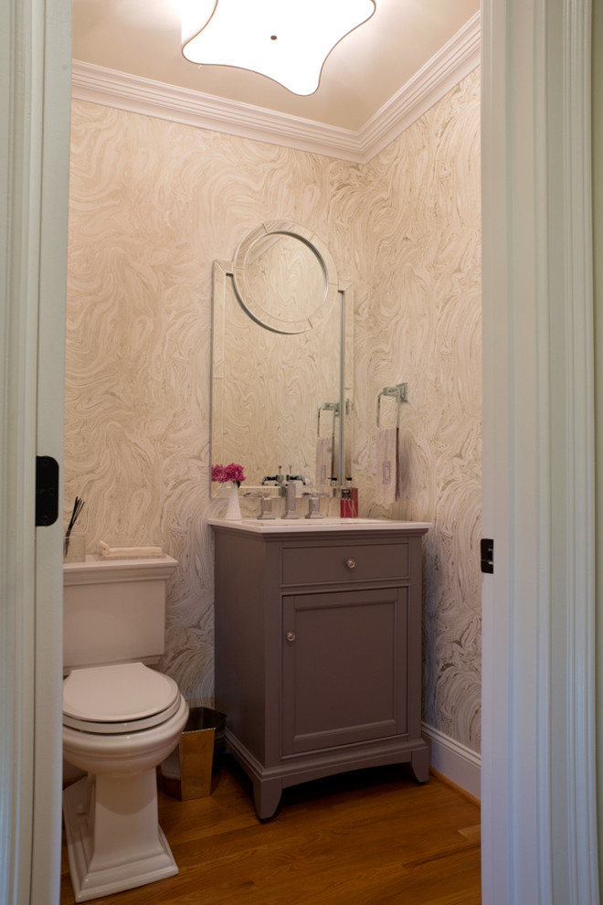 Powder room - small 1950s medium tone wood floor powder room idea in Charlotte with furniture-like cabinets, gray cabinets, a two-piece toilet, gray walls, an integrated sink and quartz countertops