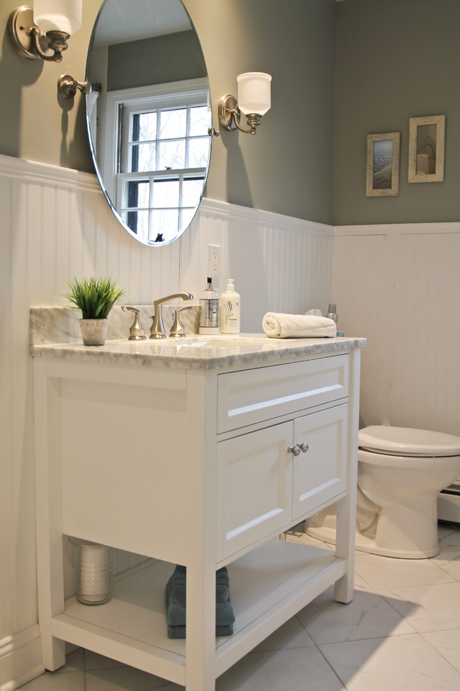 This is an example of a medium sized beach style cloakroom in Bridgeport with freestanding cabinets, white cabinets, a two-piece toilet, green walls, marble flooring, a submerged sink, marble worktops, white floors and white worktops.