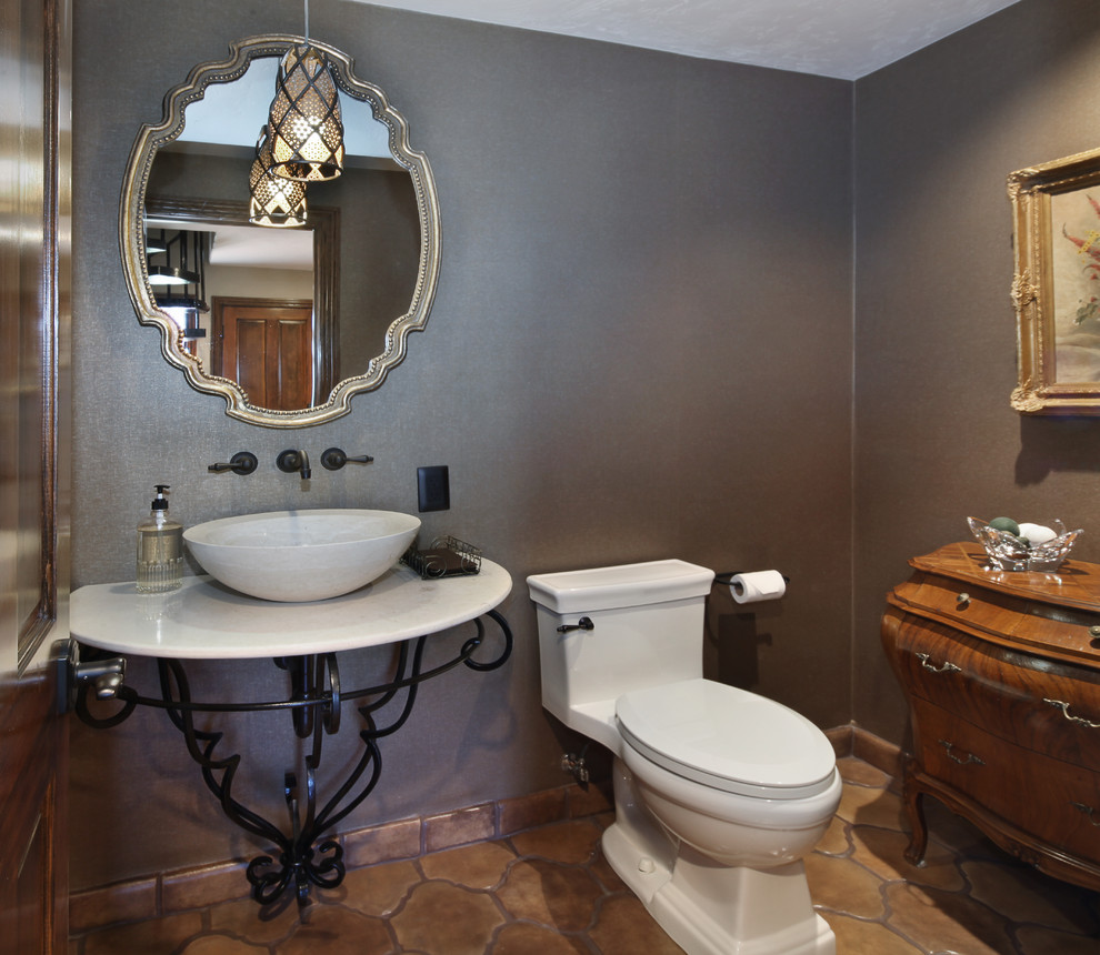 Example of a mid-sized classic terra-cotta tile powder room design in Orange County with a two-piece toilet, gray walls, a vessel sink, solid surface countertops and white countertops