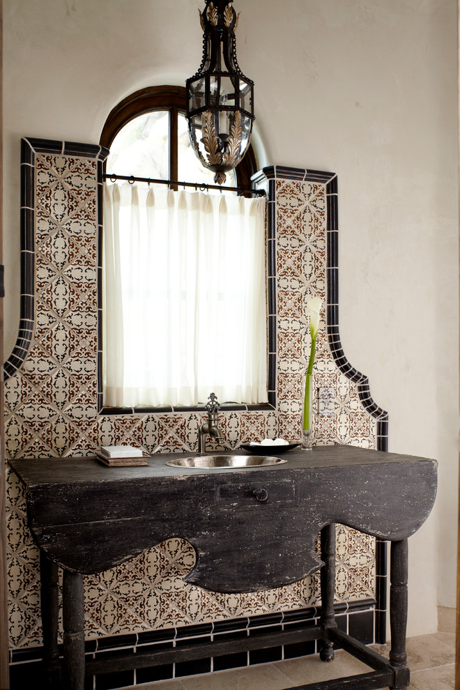 На фото: туалет среднего размера в средиземноморском стиле с накладной раковиной, бежевыми стенами, керамической плиткой, столешницей из дерева и черной столешницей с