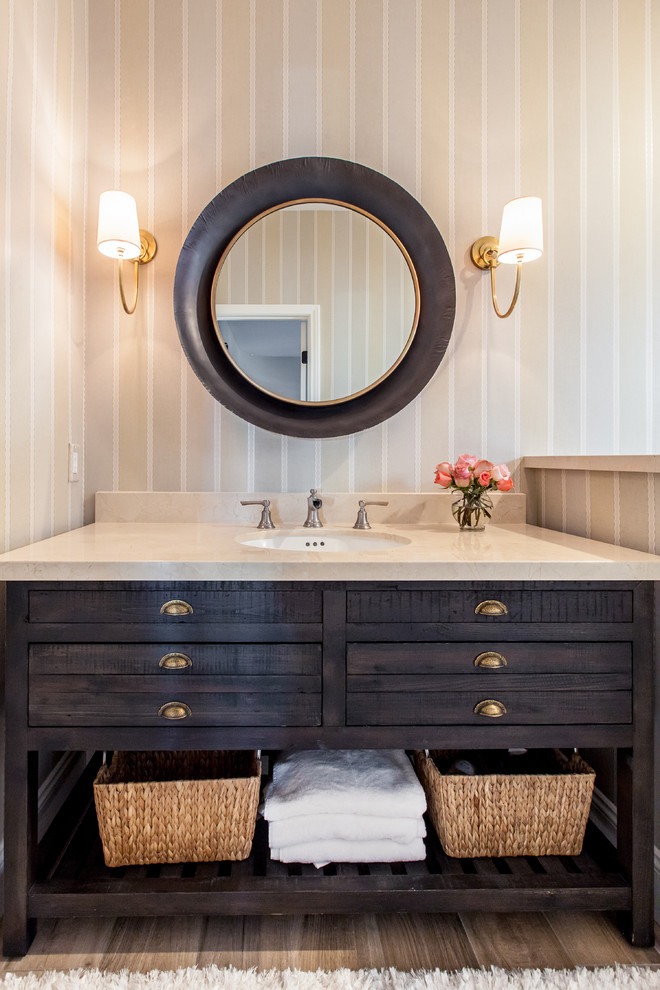 Idee per un bagno di servizio tradizionale con consolle stile comò, ante in legno bruno, pareti multicolore, parquet chiaro e lavabo sottopiano