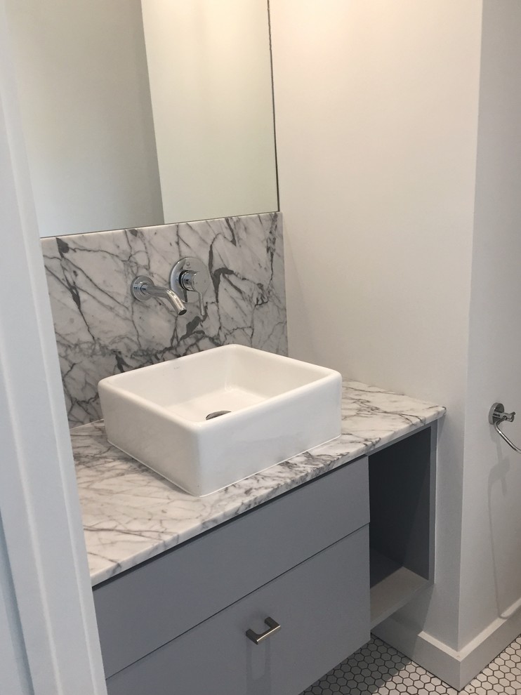 Bild på ett funkis toalett, med marmorkakel, ett fristående handfat och marmorbänkskiva