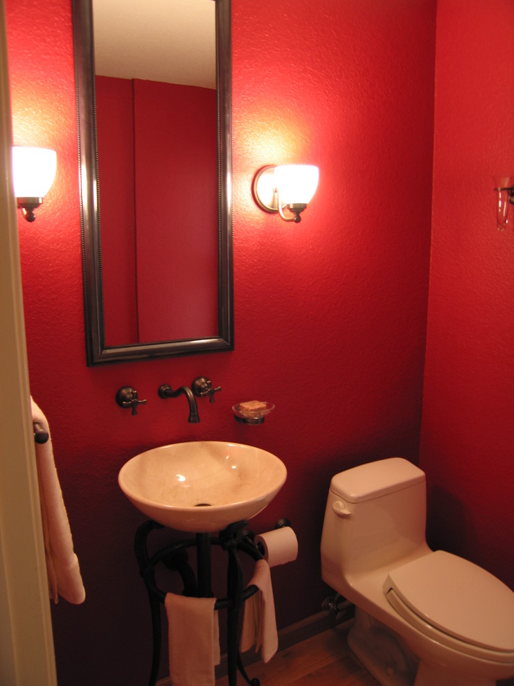 Diseño de aseo tradicional pequeño con lavabo con pedestal, sanitario de una pieza, paredes rojas y suelo de madera en tonos medios