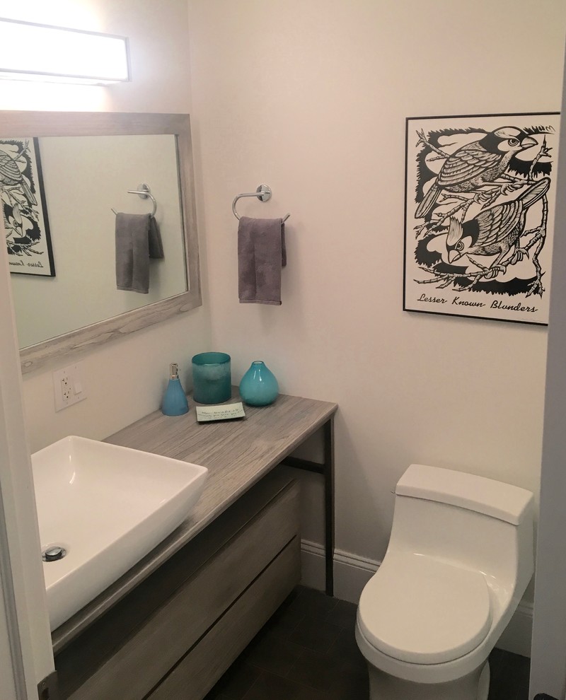 Idée de décoration pour un petit WC et toilettes design avec un placard en trompe-l'oeil, des portes de placard grises, WC à poser, un carrelage gris, un carrelage de pierre, un mur blanc, une vasque et un plan de toilette en bois.