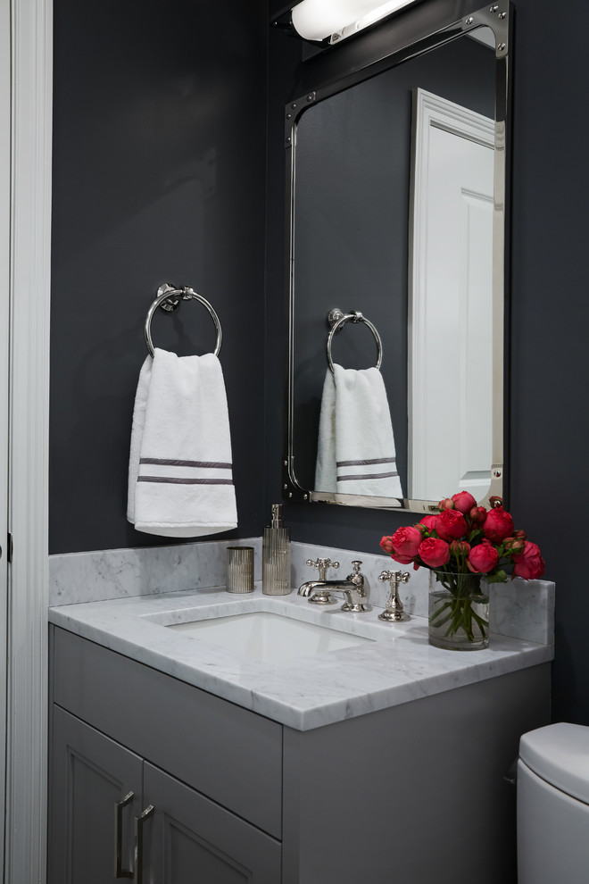 シカゴにある小さなトランジショナルスタイルのおしゃれなトイレ・洗面所 (グレーのキャビネット、黒い壁、アンダーカウンター洗面器、大理石の洗面台、落し込みパネル扉のキャビネット、白い洗面カウンター) の写真