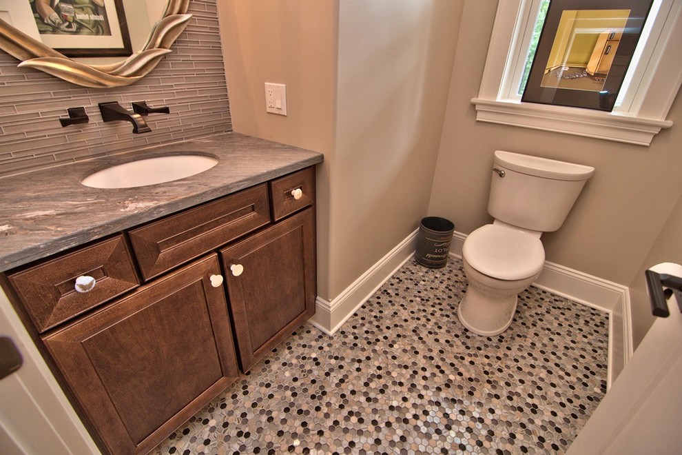 Aménagement d'un petit WC et toilettes classique en bois foncé avec un placard avec porte à panneau encastré, WC séparés, un carrelage gris, un mur beige, un sol en carrelage de terre cuite, un sol multicolore et un lavabo encastré.